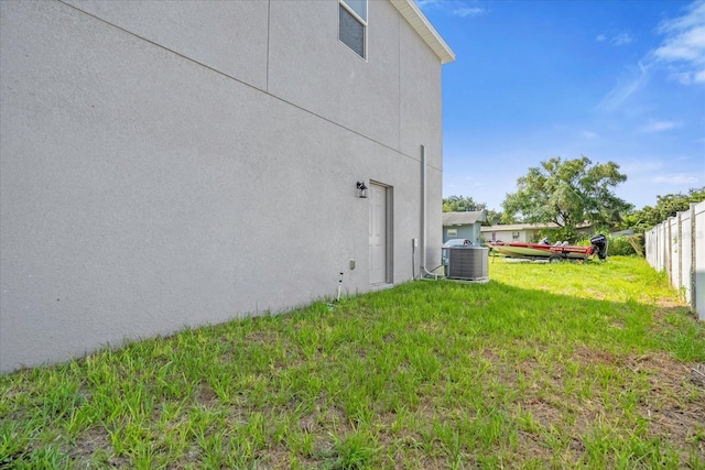 view of yard featuring fence and central AC