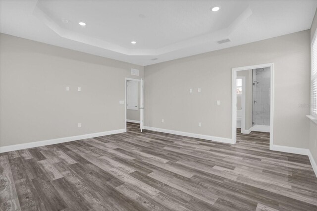 empty room with a raised ceiling and hardwood / wood-style floors