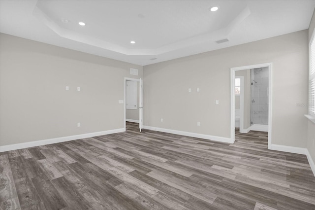 empty room featuring light wood-style floors, baseboards, a tray ceiling, and recessed lighting