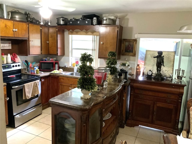 kitchen with stainless steel electric stove, light tile patterned flooring, and ceiling fan