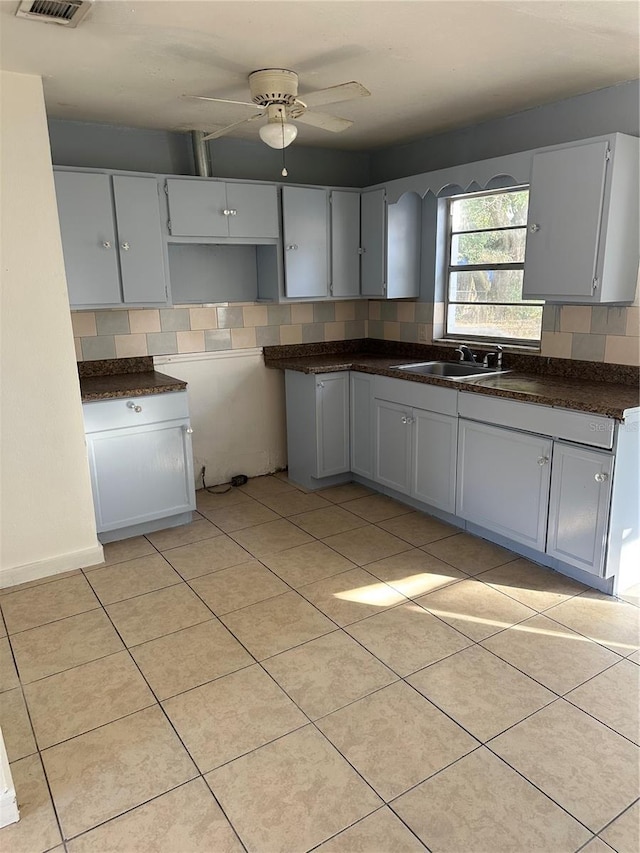 kitchen with light tile patterned floors, sink, gray cabinets, ceiling fan, and decorative backsplash