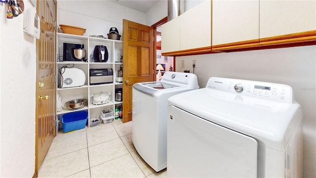 laundry area with light tile patterned floors, washing machine and clothes dryer, and cabinets