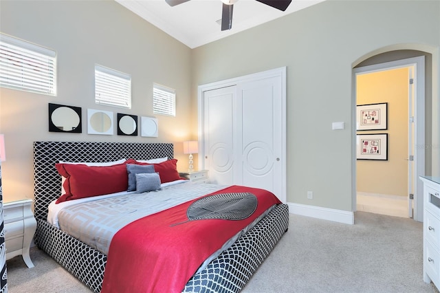 bedroom featuring multiple windows, ceiling fan, light colored carpet, and a closet