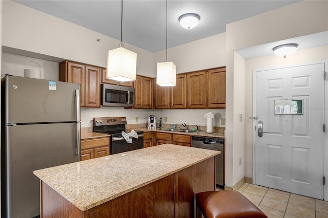 kitchen featuring light tile patterned flooring, a kitchen breakfast bar, appliances with stainless steel finishes, light stone countertops, and pendant lighting