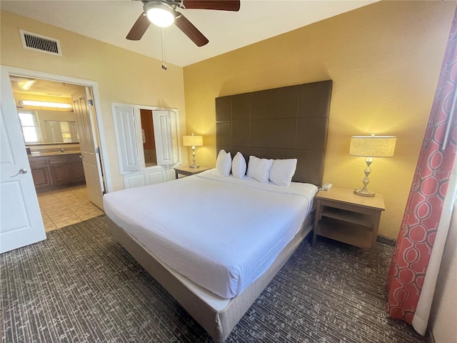 bedroom with tile patterned flooring, ceiling fan, and ensuite bath