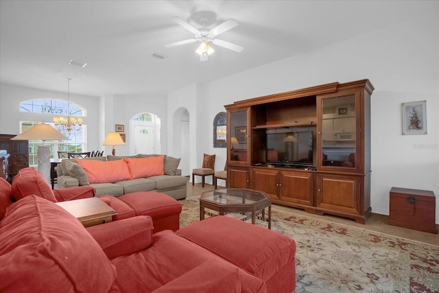 living room featuring arched walkways, ceiling fan with notable chandelier, and visible vents