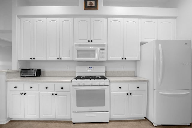 kitchen featuring white appliances, light countertops, and white cabinetry