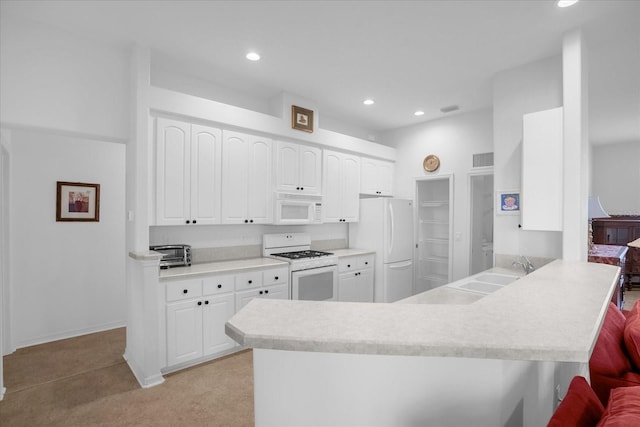 kitchen featuring a peninsula, white appliances, white cabinetry, and a sink