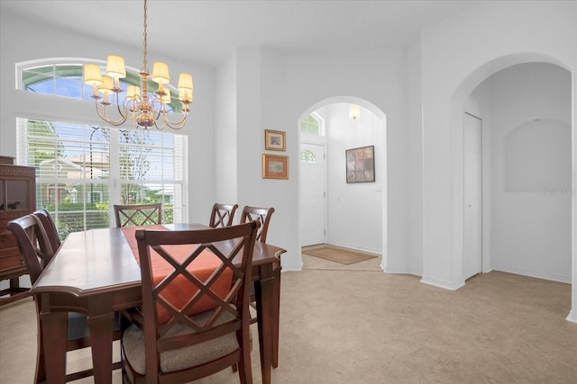 dining room featuring arched walkways, light carpet, and a notable chandelier