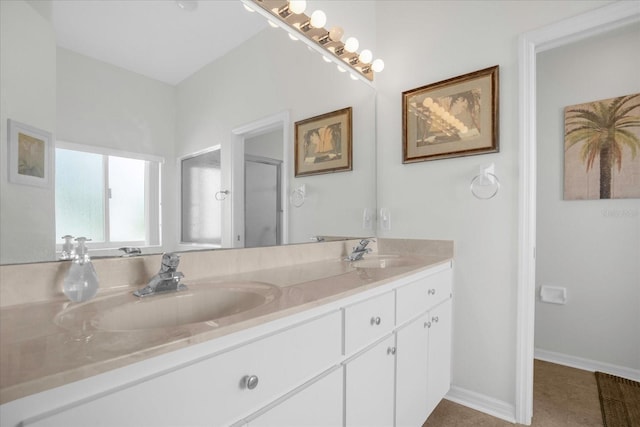 bathroom with double vanity, a sink, a shower with shower door, and baseboards