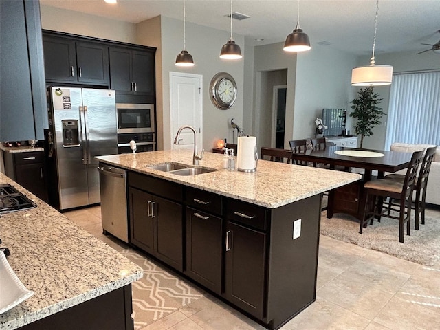 kitchen with hanging light fixtures, a kitchen island with sink, appliances with stainless steel finishes, light tile patterned floors, and sink