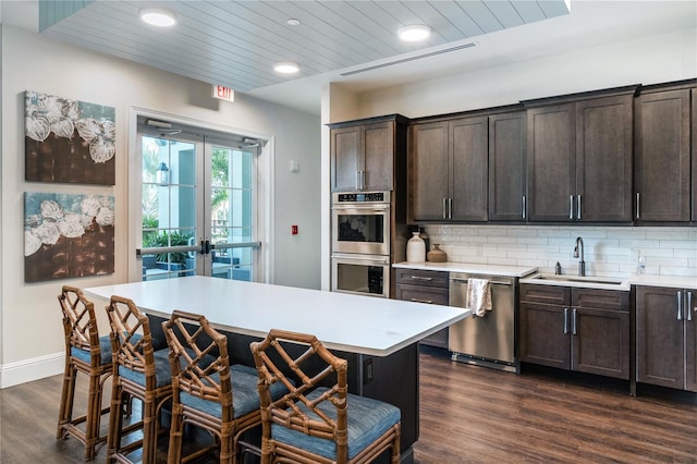 kitchen featuring backsplash, dark brown cabinetry, dark hardwood / wood-style flooring, appliances with stainless steel finishes, and sink