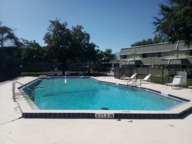 pool with a patio area and fence