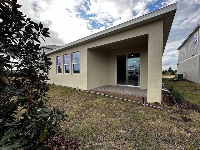 rear view of house featuring central AC and a lawn