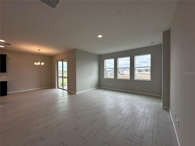 spare room featuring light hardwood / wood-style flooring and a notable chandelier