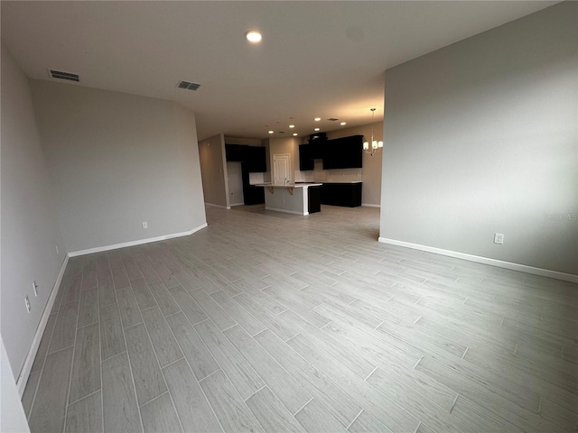 unfurnished living room featuring hardwood / wood-style floors and a notable chandelier