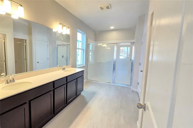 bathroom with hardwood / wood-style floors, vanity, and a shower with door