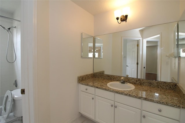 bathroom featuring vanity, toilet, and tiled shower