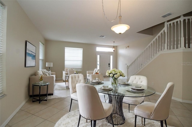 dining room featuring light tile patterned floors, visible vents, baseboards, and stairs