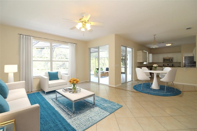 living area with a ceiling fan, visible vents, baseboards, and light tile patterned floors