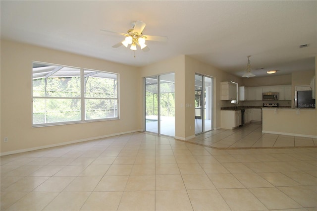 unfurnished living room featuring light tile patterned floors, a ceiling fan, visible vents, and baseboards