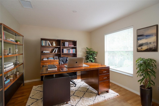 office space featuring visible vents, baseboards, and wood finished floors