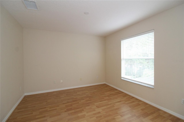 spare room featuring light wood-style floors, visible vents, and baseboards