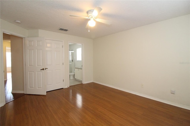 unfurnished bedroom with ensuite bathroom, ceiling fan, and wood-type flooring