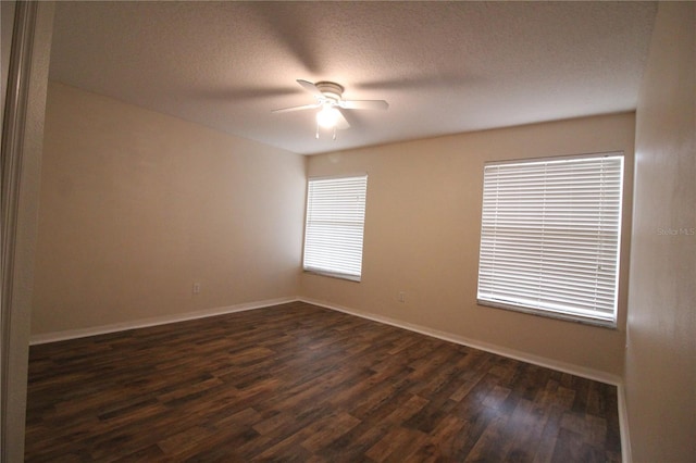 empty room with dark wood-style floors, ceiling fan, baseboards, and a textured ceiling