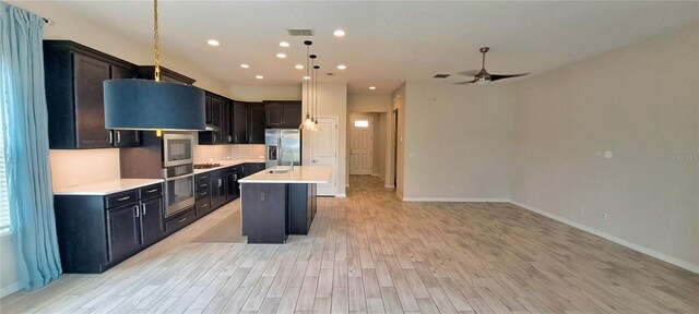 kitchen featuring light hardwood / wood-style flooring, hanging light fixtures, backsplash, stainless steel appliances, and a center island