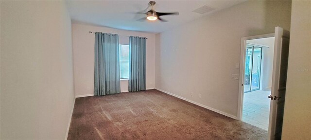 empty room featuring ceiling fan and dark carpet