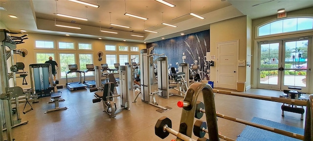 workout area featuring a towering ceiling, a wealth of natural light, and french doors