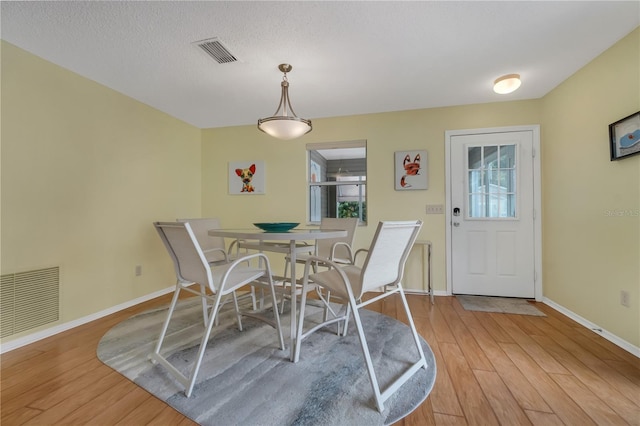 dining area featuring a textured ceiling, a healthy amount of sunlight, and wood-type flooring