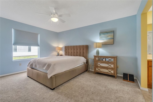 carpeted bedroom featuring ceiling fan and ensuite bath