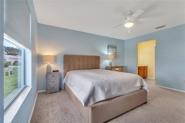 bedroom with ceiling fan, connected bathroom, light colored carpet, and multiple windows