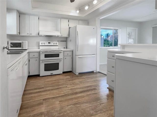 kitchen featuring white appliances, white cabinets, rail lighting, and hardwood / wood-style flooring