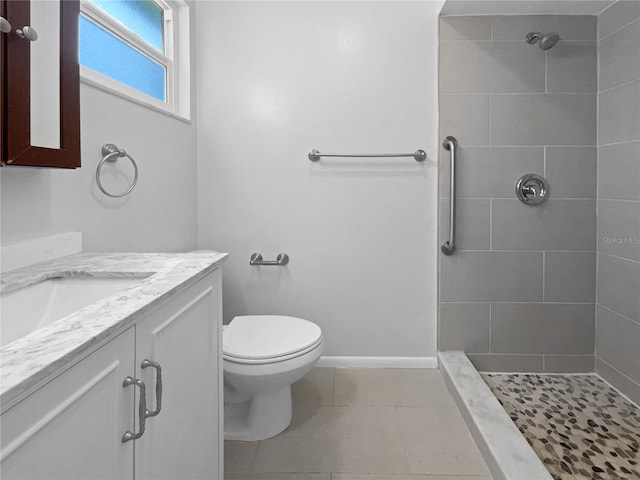 bathroom featuring toilet, a tile shower, tile patterned flooring, and vanity