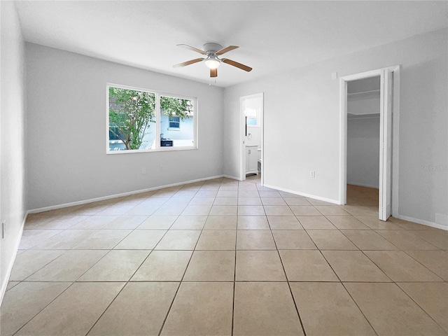 unfurnished bedroom with ceiling fan, a closet, a spacious closet, and light tile patterned flooring