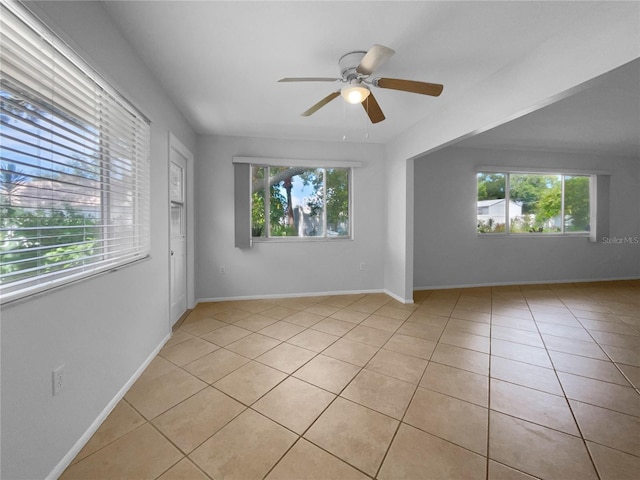 spare room with ceiling fan, plenty of natural light, baseboards, and light tile patterned floors