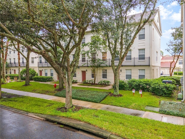 view of front facade with a balcony and a front yard