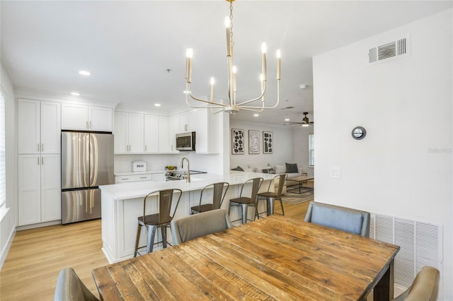 dining area featuring light wood-type flooring and ceiling fan with notable chandelier