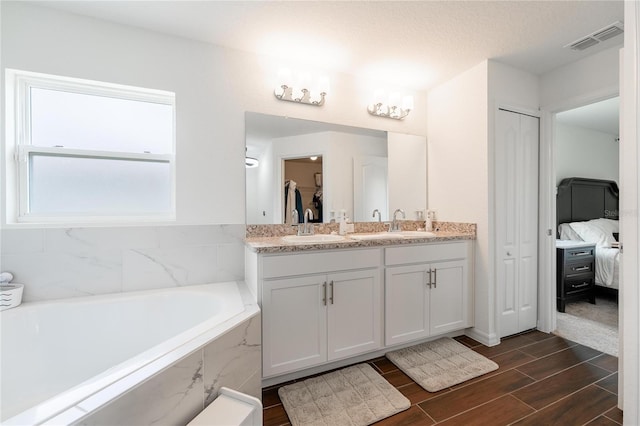 bathroom featuring a relaxing tiled tub and vanity