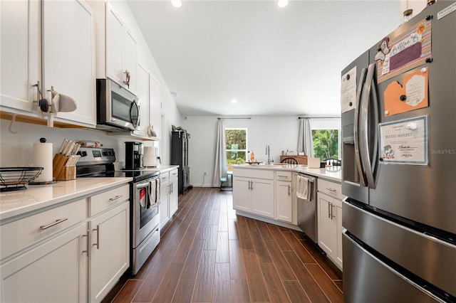 kitchen with dark hardwood / wood-style flooring, white cabinetry, appliances with stainless steel finishes, light stone counters, and sink