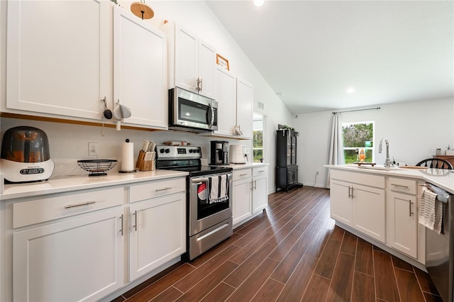 kitchen with stainless steel appliances, dark hardwood / wood-style floors, sink, lofted ceiling, and white cabinets