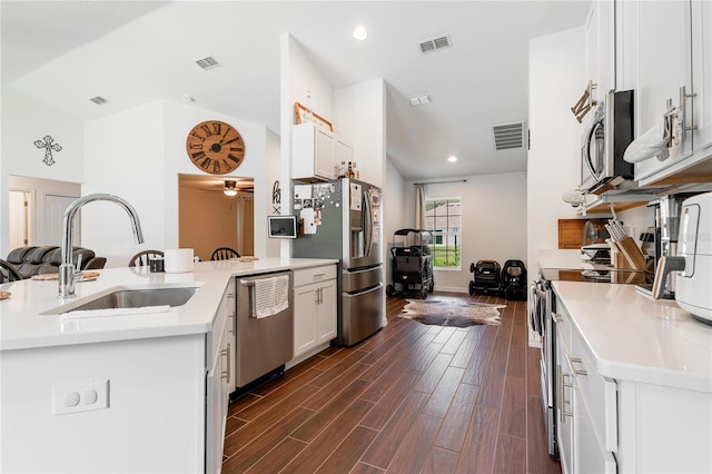 kitchen with appliances with stainless steel finishes, white cabinetry, dark hardwood / wood-style floors, sink, and ceiling fan