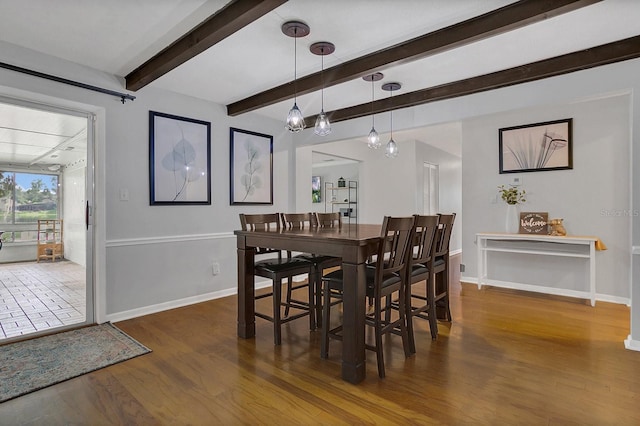 dining space featuring beam ceiling, baseboards, and wood finished floors