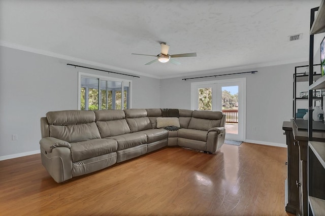 living room featuring plenty of natural light, visible vents, crown molding, and wood finished floors