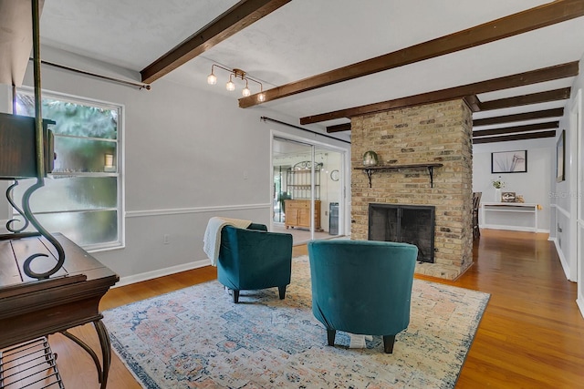 living area featuring a fireplace, baseboards, wood finished floors, and beamed ceiling