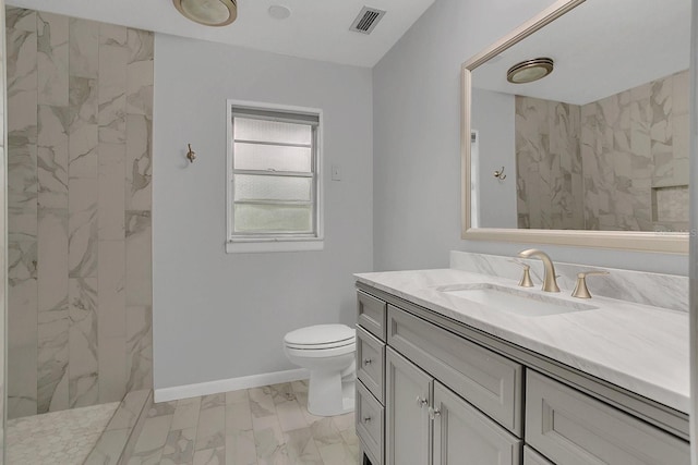 bathroom featuring marble finish floor, a marble finish shower, toilet, vanity, and baseboards