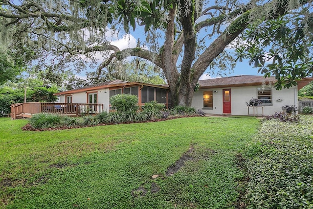 ranch-style home with a front yard, a sunroom, and a deck